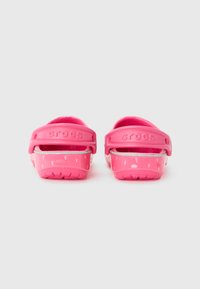Infradito Crocs rosa con una finitura lucida e texture. Presentano una fascia larga e una suola decorata. Marchio visibile sulla fascia del tallone.