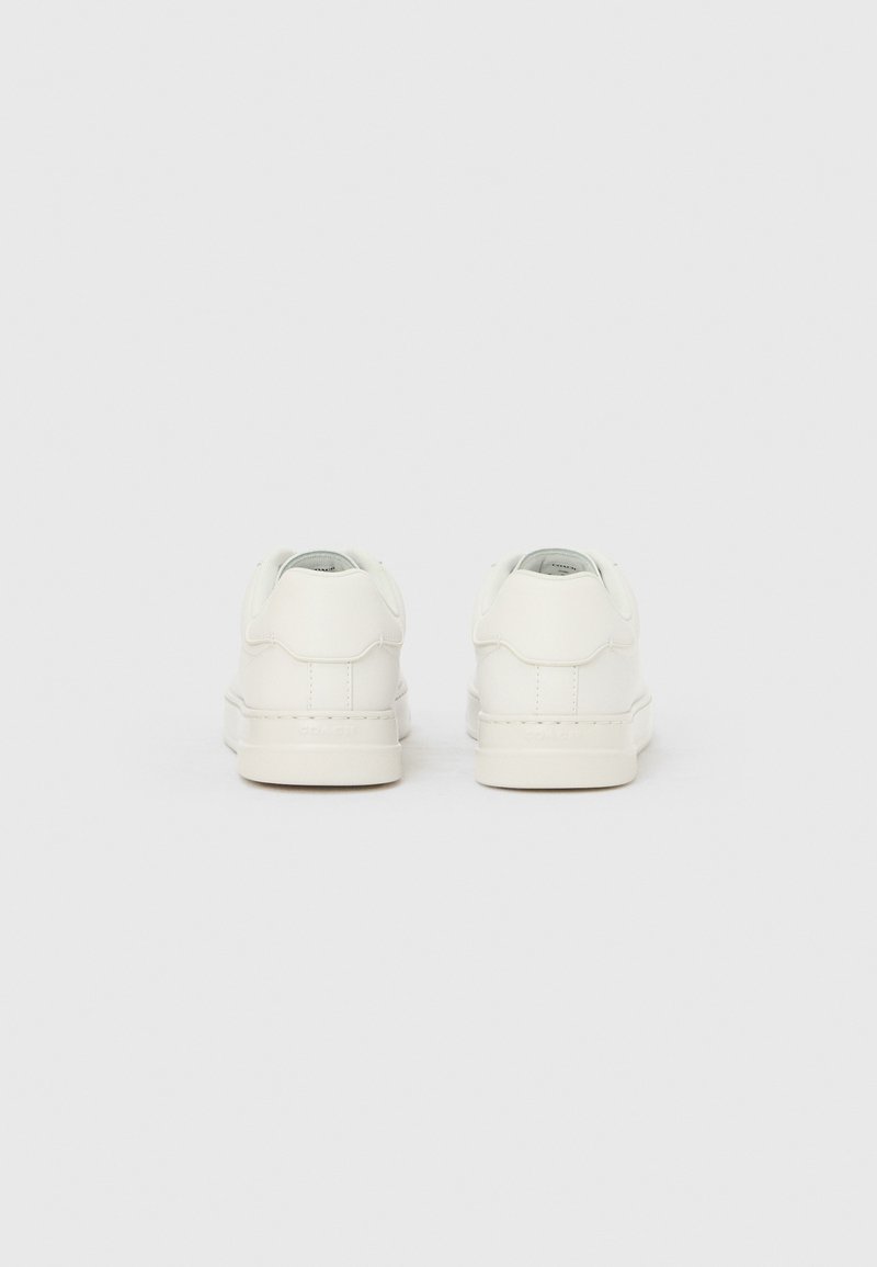 Baskets en cuir blanc au design bas, texture lisse, accents minimalistes et languettes de talon arrondies. Esthétique simple et épurée.