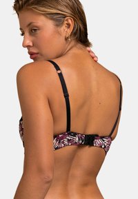 Haut de bikini avec des bretelles noires ajustables, un motif floral coloré et une fermeture à clip au dos. Texture de tissu lisse avec un design ajusté.