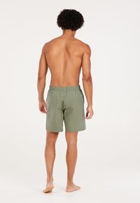 Groene zwemshorts met een elastische tailleband, gemaakt van lichte materialen, met een gladde textuur en een eenvoudig ontwerp.