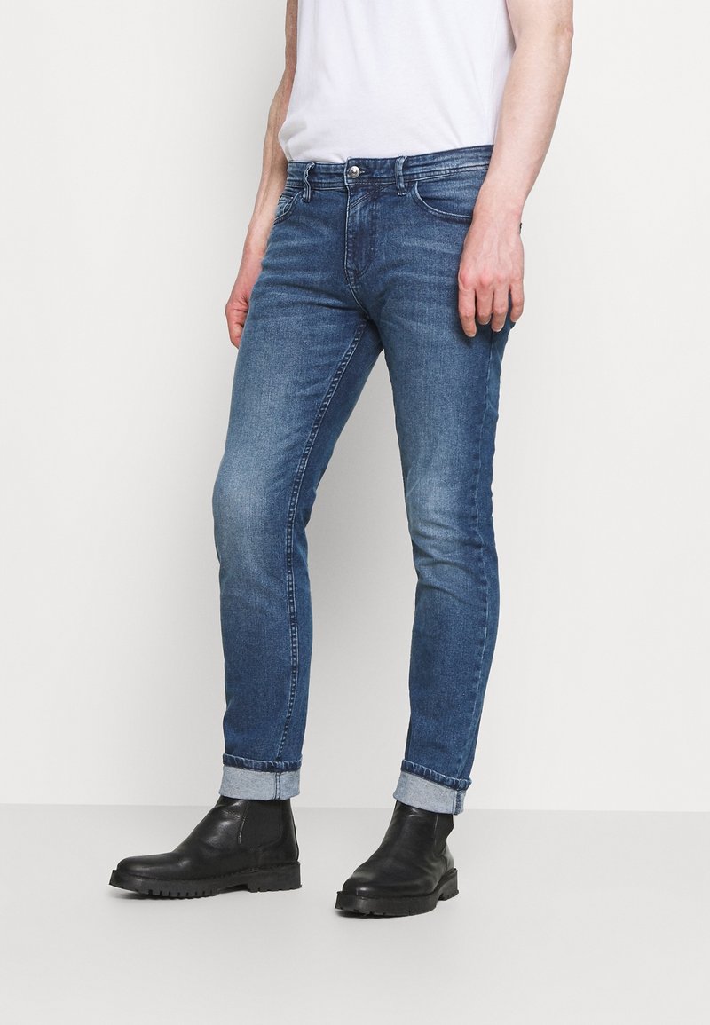 Blå denim skinny jeans med en blekt finish, med en klassisk femfickdesign och uppvikta benslut, kombinerat med svarta ankelboots.