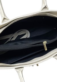 Bílá texturovaná kabelka se zipovým uzavřením. Interiér má podšívku z černé látky a zipovou kapsu. Dvě ramenní popruhy.