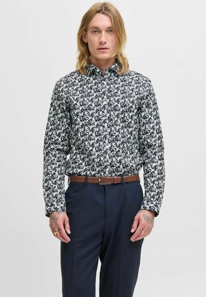 Floral Hemd mit Knöpfen in Schwarz und Weiß, schlanke Passform, lange Ärmel und dezente Blumenmuster; kombiniert mit dunklen Hosen und einem braunen Gürtel.