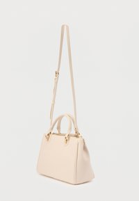 Μπεζ δερμάτινη τσάντα χειρός με διπλές λαβές, χρυσά μεταλλικά στοιχεία και ρυθμιζόμενο, μακρύ λουρί ώμου, σε απλό ανοιχτό φόντο.