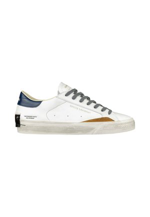 Sneaker in pelle bianca con lacci grigi, tallone blu navy e un'accorta in camoscio marrone. Il testo sul lato recita: "DISTRESSED WITH NO STRESS."
