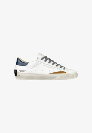 Sneaker in pelle bianca con lacci grigi, tallone blu navy e un'accorta in camoscio marrone. Il testo sul lato recita: "DISTRESSED WITH NO STRESS."