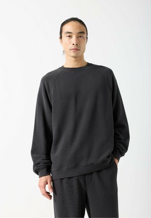 Dark gray sweatshirt with a round neckline, raglan sleeves, and ribbed cuffs. The fabric has a textured finish. Paired with matching pants.