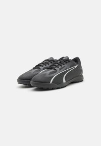 Czarne buty sportowe z teksturowaną cholewką, z białymi akcentami i czarną podeszwą z wzorami zapewniającymi przyczepność. Zdecydowany system sznurowania.