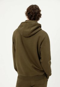 Oliwkowa bluza z kapturem z prążkowanym dołem i mankietami, z sznurkiem do regulacji. Wykonana z miękkiego, fakturowanego materiału, zaprojektowana z myślą o komforcie.