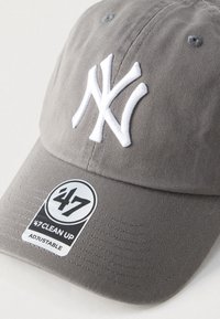 Γκρι ρυθμιζόμενο καπέλο μπέιζμπολ με λευκό κεντητό λογότυπο NY. Διαθέτει ραβδωτή υφή και κυκλικό ετικέτα λογότυπου με τη σήμανση '47 CLEAN UP'.