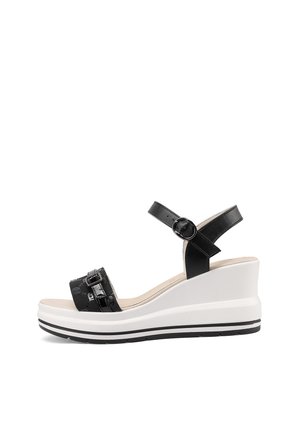 Sandalo zeppa bianco e nero con cinturino alla caviglia, chiusura con fibbia e suola texturizzata, mostrato di profilo su sfondo bianco.