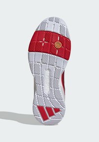 Shoe sole with a white base, red midsection, and textured patterns. Features a circular accent in yellow and three textured stripes in red.