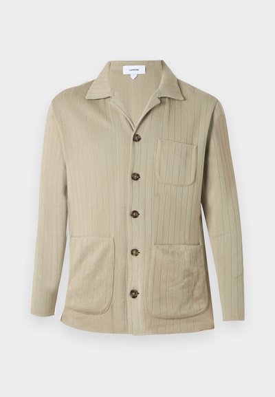 Μπεζ πουκάμισο με μακριά μανίκια και κουμπιά, με διακριτική ριμπ υφή, γιακά με εγκοπές, μπροστινή τσέπη και δύο κάτω τσέπες τύπου patch.