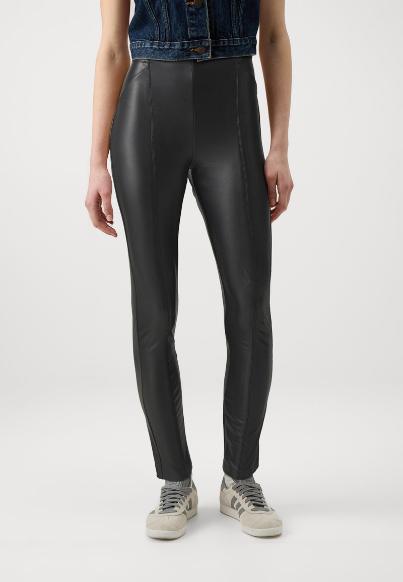 Fekete műbőr leggings magas derékkal, sima felülettel és testhezálló fazonnal. Az elülső és hátsó lábak mentén függőleges varrások találhatók.