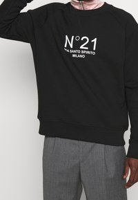 Felpa nera con collo rotondo e maniche raglan. Presenta una scritta bianca stampata "N°21 via Santo Spirito Milano" sul davanti.