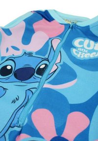 Body léger bleu avec un personnage de dessin animé au visage rond, grands yeux, et motifs floraux en rose et bleu. Fermeture éclair à l'avant.