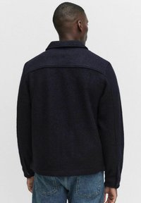 Laivastonsininen villasekoitekotelotakki, jossa on rakennettu kaulus, napitettu hihansuun ja rento istuvuus. Teksturoitu kangas, jossa on hienovaraisia vaihteluita.