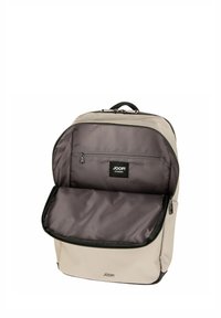 Zaino in tessuto beige con una texture liscia, dotato di un ampio scomparto principale e una tasca interna con zip. Marchio JOOP! visibile.