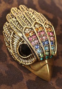 Złota broszka w kształcie pióra z kolorowymi cyrkoniami w różnych odcieniach. Oferuje czarny kamień w centrum i misternie wykonane detale.