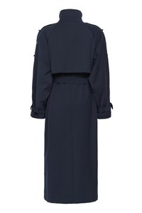 Laivastonsininen trenssitakki, joka on valmistettu sileästä kankaasta, ja siinä on vyötäröllä vyö, pitkät hihat kalvosimilla sekä lyhennetty takamalli.