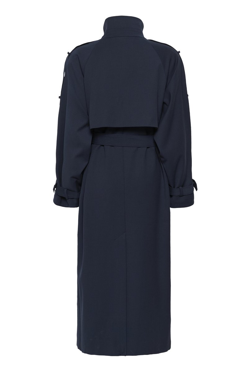Trench-coat bleu marine en tissu lisse, doté d'une taille ceinturée, de manches longues avec bracelets aux poignets, et d'un dos raccourci.