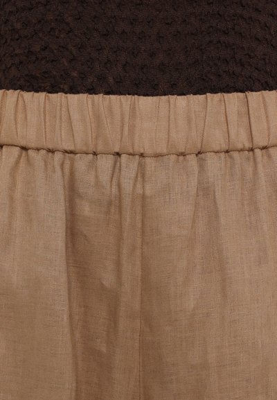 Brązowa teksturowana tkanina na górze z luźnym beżowym lnianym pasem poniżej, z marszczeniami wzdłuż szwu.