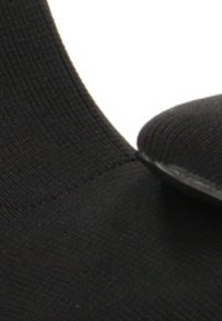 Primer plano de una bota de tobillo de tela negra con textura de punto acanalada visible y panel elástico frontal.