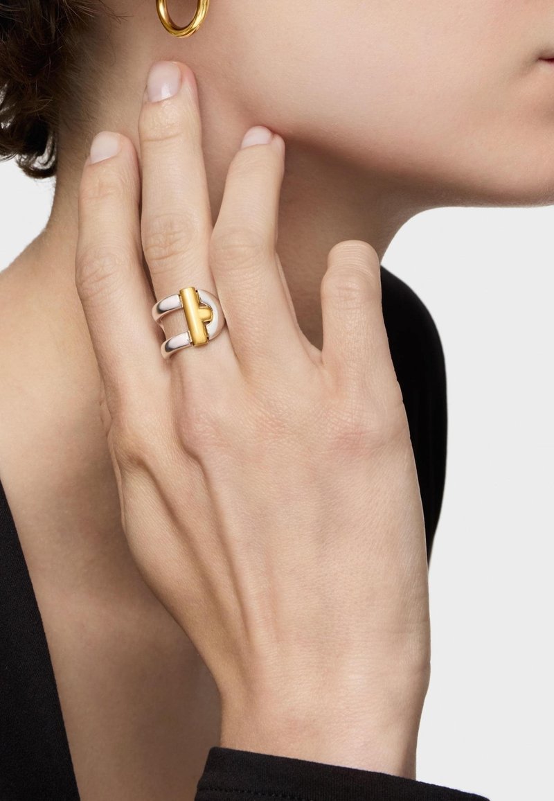 Silver and gold ring featuring a geometric design. The band is smooth with a polished surface, showcasing a gold accent in the center.
