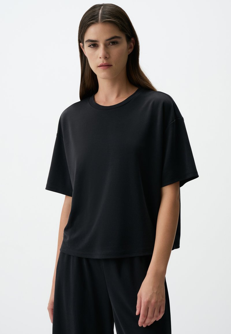 Zwart t-shirt met korte mouwen, gemaakt van zacht stof, met een relaxte pasvorm en een ronde halslijn. Geen zichtbare patronen of accenten.