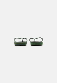 Grønne flip-flops med en teksturert såle, tynne stropper og en kontrastfarge i svart. Designet med minimalistiske trekk og en lett profil.