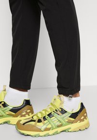 Sneakers med en mix av svart, gult och grönt, ett texturerat mesh-överstycke och ett framträdande snörningssystem. Hållbar gummisula.