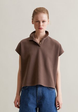 Koffiekleurig polo shirt met korte mouwen, een kraag en drie knopen, gemaakt van textuurstof. Gecombineerd met hoge blauwe denim shorts.