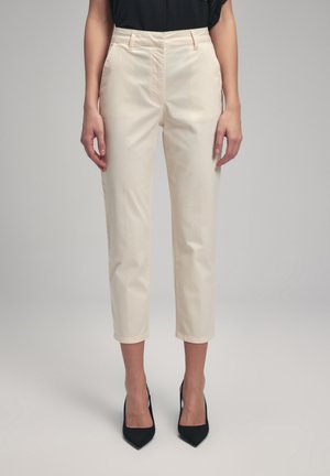 Beige cropped trousers made of smooth fabric, featuring a high waist, slant pockets, and a straight leg design, paired with black heels.
