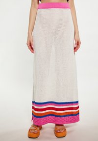 Witte gebreide maxi-rok met een roze tailleband, met horizontale strepen in blauw, rood, oranje en roze aan de zoom.