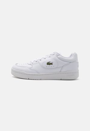 White low-top sneaker with lace-up front, perforated toe, padded collar, and green Lacoste crocodile logo on the side.