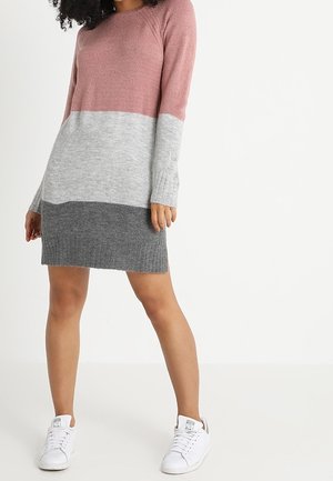 Vestito di maglia con design a blocchi di colore in rosa, grigio e grigio scuro, con maniche lunghe e orlo a costine. Abbinato a sneakers bianche.