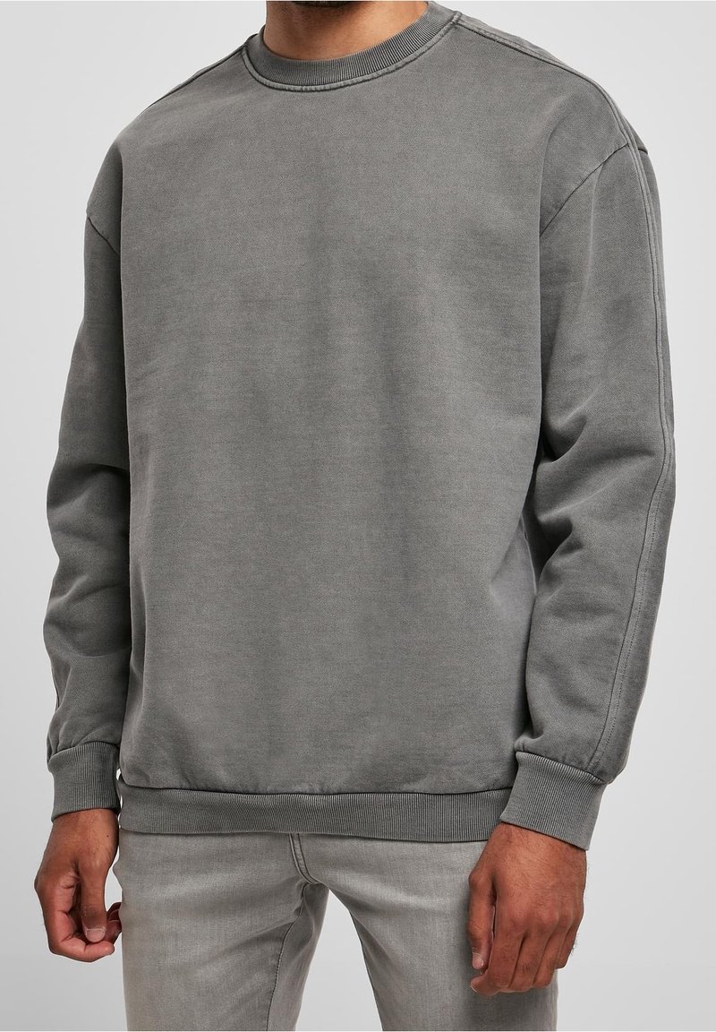 Sudadera de algodón gris con cuello redondo clásico, puños y bajo acanalados. Presenta una textura suave y un ajuste relajado.