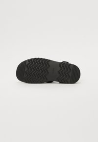 Black rubber sandal sole featuring a zigzag tread pattern and a textured surface. The brand name "ALDO" is visible on the side.