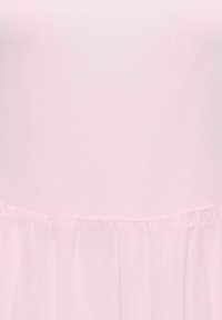 Miękka różowa tkanina z szwem dzielącym górną, gładką część oraz dolną część marszczoną, tworzącą delikatne plisy.