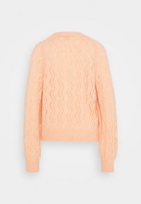 Pull tricoté couleur pêche avec un motif en zigzag, ourlet et poignets côtelés, manches longues, et texture ajourée. Vue de dos visible.