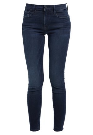 Tummansiniset skinny-farkut, joissa on klassinen viiden taskun muotoilu, vyölenkit ja edessä nappisuljenta.