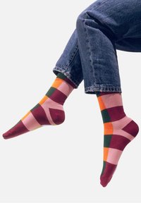 Wielokolorowe skarpetki z geometrycznym wzorem w odcieniach różu, zieleni, pomarańczy i burgunda. Wykonane z miękkiego, elastycznego materiału.