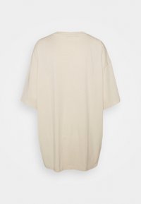 Béžové oversized bavlněné tričko s kulatým výstřihem a krátkými rukávy, s hladkým, jednobarevným povrchem. Zobrazeno zezadu.