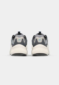 Gray and white sneakers with a textured mesh upper, rubber outsoles, and a pull tab at the heel; features a light blue logo on the back.