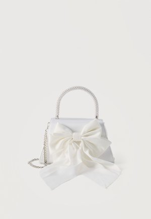 White handbag with pearl handle, silver chain strap, and large fabric bow on front.