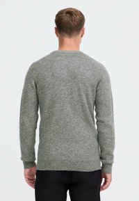 Hallide kudumistega hall sall, millel on pikad varrukad, ümar kaelus ja tekstuuriga viimistlus, omades mõjutatud lõiget ja soonikvarrukaid.