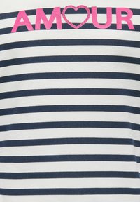 Chemise à manches courtes rayée en blanc et bleu marine. Comporte des lettres roses audacieuses formant le mot « AMOUR » avec un accent cœur. Matière en coton doux.