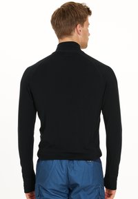 Zwart langemouwen top met een hoge kraag, gemaakt van een gladde stof met raglanmouwen en minimale stikaccenten.