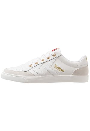 Hvid lav sneaker med gyldne snørehuller, gyldent ""hummel STADIL LIMITED"" logo, chevron-design på siden og beige ruskindspaneler ved tå og hæl.