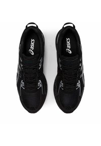 Pantofi sport negri cu un superior din plasă respirabilă, având accente reflective și o talpă cu amortizare. Șireturile sunt fixate în zona medie a piciorului.